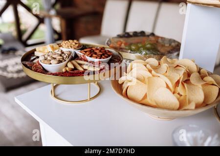Vorspeisentisch mit verschiedenen Antipasti, Wurstwaren, Snacks, Auswahl an Nüssen, Käse, Kartoffelchips. Fingerfood für Buffetparty. Traditionelles fre Stockfoto