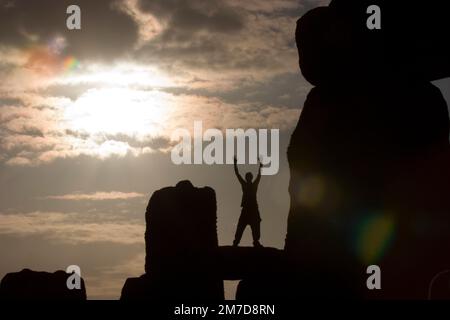 Die Sonne ist hinter den alten Steinen von Stonehenge, Wiltshire, England am 21. Juni Mittsommer-Tag und der längste Tag des Jahres steigen, wie große Massen von Feiernden und Schaulustige versammeln sich, um die Sommersonnenwende Zeuge ersichtlich. Stockfoto