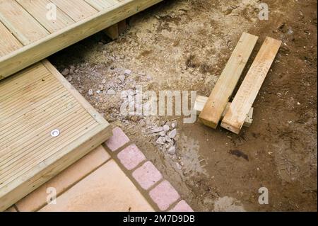 Vorbereitung harter Steh- und Terrassenbereiche in einem kleinen Garten und Auslegen von Pflanzen zum Pflanzen. Stockfoto