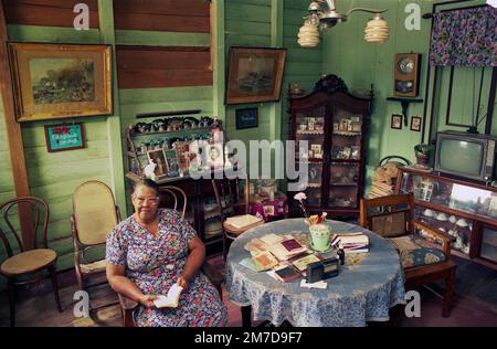 Surinam, ältere Frau sitzt in ihrem Wohnzimmer in einem Holzhaus, das typisch für die Architektur in Paramaribo und zwischen holländischem Pelz ist Stockfoto