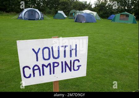 Ein Campingplatz, der in verschiedene Bereiche unterteilt wurde, einschließlich Jugend-, gemischte und Familien-Camping, indem Schilder im Gras aufgeworfen wurden. Stockfoto