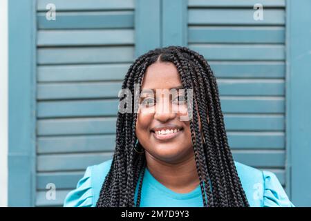 Eine afroamerikanische Frau mit Zöpfen stand auf der Straße und schaute in die Kamera. Stockfoto