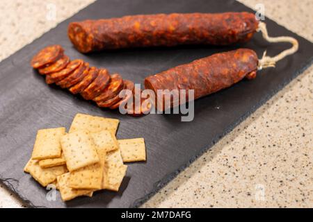 Authentische Chorizo ​​from León, in dünne Scheiben geschnitten, auf einem Schieferstein präsentiert, hergestellt aus verschiedenen iberischen Schweinefleisch Stockfoto
