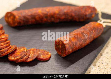 Authentische Chorizo ​​from León, in dünne Scheiben geschnitten, auf einem Schieferstein präsentiert, hergestellt aus verschiedenen iberischen Schweinefleisch Stockfoto