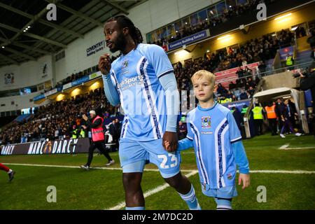 Der Fankaty Dabo von Coventry City betritt das Spielfeld mit einem Maskottchen vor dem dritten Spiel des Emirates FA Cup in der Coventry Building Society Arena in Coventry. Foto: Samstag, 7. Januar 2023. Stockfoto