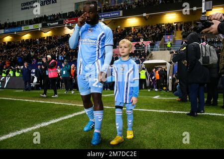 Der Fankaty Dabo von Coventry City betritt das Spielfeld mit einem Maskottchen vor dem dritten Spiel des Emirates FA Cup in der Coventry Building Society Arena in Coventry. Foto: Samstag, 7. Januar 2023. Stockfoto