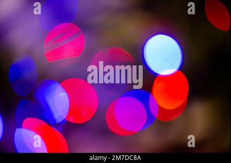 Hintergrund voller unfokussierter, farbenfroher Lichter. Unscharfe Lichterspuren und Flecken von Weihnachtsbäumen. Stockfoto