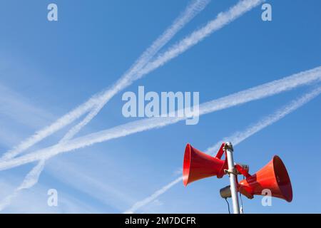 Ein paar rote Lautsprecher oder Hörner vor blauem Himmel gesetzt und verwendet, um Ankündigungen bei öffentlichen Veranstaltungen, ein PA-System zu machen. Stockfoto