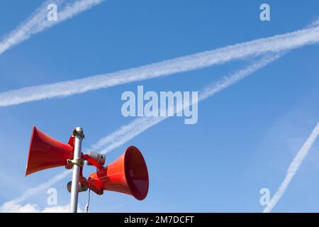 Ein paar rote Lautsprecher oder Hörner vor blauem Himmel gesetzt und verwendet, um Ankündigungen bei öffentlichen Veranstaltungen, ein PA-System zu machen. Stockfoto