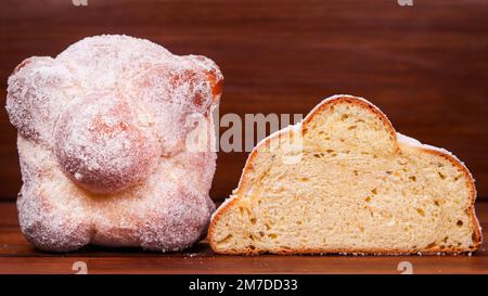 Eine Nahaufnahme von Pan de Muerto-Brot, ein ganzes und ein weiteres auf einer Holzfläche Stockfoto