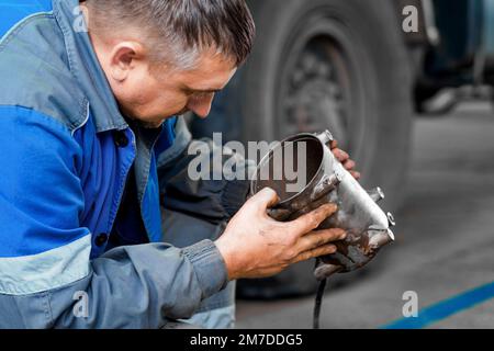 Automechaniker repariert Lkw. Professionelle Reparatur und Diagnose von Frachttraktoren und -Ausrüstung. Der Mechaniker in der Werkstatt berücksichtigt Ersatzteile. Stockfoto