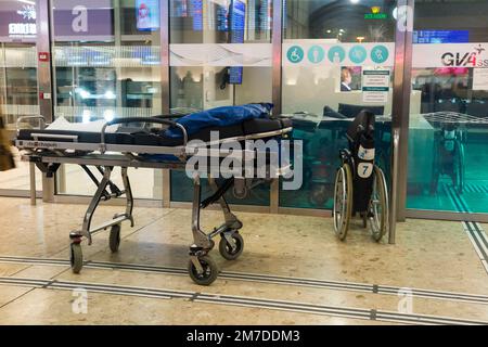 Am Genfer Cointrin International Airport in der Schweiz steht eine Trage und ein Rollstuhl bereit, um Passagieren / Flughafenhilfe oder behinderten medizinischen Notfallreisenden zu helfen. (133) Stockfoto