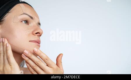 Erwachsene Frau, die Gesichtskinesiologie-Klebeband auf ihr Gesicht aufklebt Hautpflege. Stockfoto