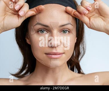 Erwachsene Frau, die Gesichtskinesiologie-Klebeband auf ihr Gesicht aufklebt Hautpflege. Stockfoto