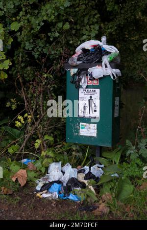 Ein Abfalleimer in einem Park bietet Hundegängern oder Besitzern die Hundeklamotten, die sie auf einem Spaziergang mitgenommen haben, abzulegen, wird mit Plastiktüten gezeigt. Stockfoto