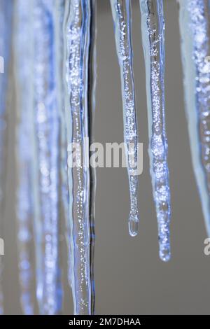 Großen Eiszapfen hängen von einem Haus glitzern im Sonnenlicht wie Juwelen aus Kristall oder Glas Winter. Stockfoto
