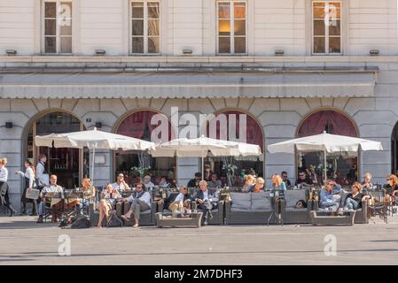 Café piazza Italy, im Sommer Blick auf die Gäste, die an Cafétischen auf der Piazza Unita d'Italia in Triest, Friaul-Julisch Venetien, Italien sitzen Stockfoto