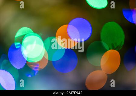 Hintergrund voller unfokussierter, farbenfroher Lichter. Unscharfe Lichterspuren und Flecken von Weihnachtsbäumen. Stockfoto