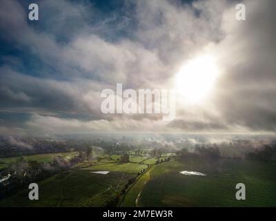 Ein nebeliger Sonnenaufgang über Cirencester in den Cotswolds, Gloucestershire. Stockfoto