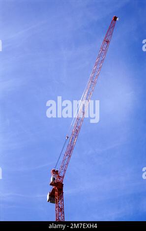 Großer roter Kran auf einer Baustelle vor einem blauen Himmel. Stockfoto