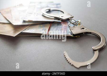 silberne Handschellen an vielen großen Euro-Banknoten Stockfoto