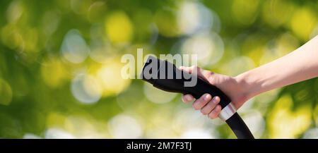 Hand mit Ladestecker für Elektroauto auf grünem Hintergrund Stockfoto