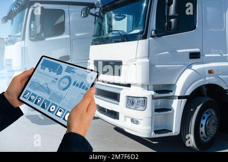 Manager mit einem digitalen Tablet neben Trucks. Flottenmanagement Stockfoto