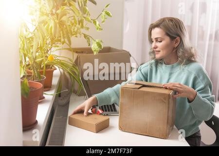 Nahaufnahme eines weiblichen Online-Shops, Inhaber eines kleinen Unternehmens, Unternehmer, der Verpackungspakete nach dem Versand vorbereiteter Versandkarton auf dem Tisch vorbereitet Stockfoto