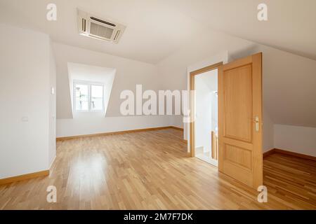 Geräumiges Zimmer auf dem Dachboden eines Einfamilienhauses mit Dachfenstern, Eichenboden, Klimaanlage an der Decke und Aluminiumheizkörpern Stockfoto