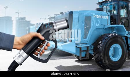 Hand mit Wasserstoff-Betankungsdüse auf dem Hintergrund von Brennstoffzellenbaumaschinen. Konzept Stockfoto