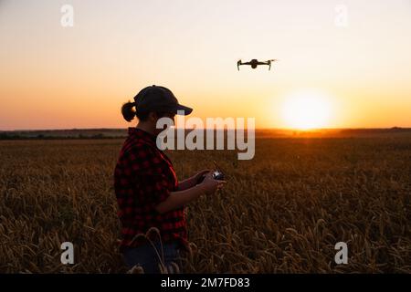 Der Bauer steuert die Drohne mit einem Tablet bei Sonnenuntergang. Intelligente Landwirtschaft und Präzisionslandwirtschaft Stockfoto