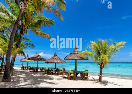 Strandcafe am Sandstrand, Tische unter Strohschirmen, Palmen und wunderschönes Meer auf exotischen tropischen Inseln. Stockfoto