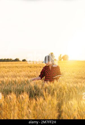 Eine Frau Bauer untersucht den Bereich der Getreide- und sendet die Daten an die Wolke aus der Tablette. Smart Farming und digitale Landwirtschaft. Stockfoto