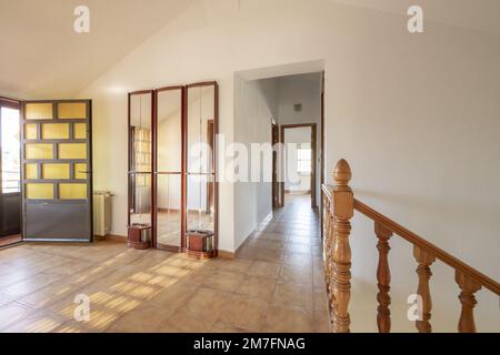 Innentreppen mit Holzgeländer in einem Einfamilienhaus mit langen Korridoren und großen Bereichen mit Zugang zu einer Terrasse Stockfoto