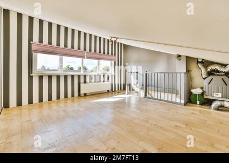 Ein leeres Wohnzimmer mit Holzfußboden und gestreiften Tapeten an den Wänden in Schwarz-Weiß-Streifen Stockfoto
