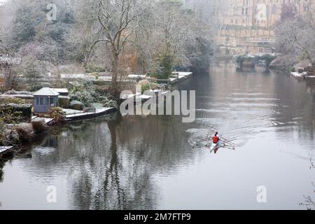 Ruderfahrer rudern auf dem Fluss Avon, während er nach einem leichten Schneefall im Winter durch Warwickshire fließt Stockfoto