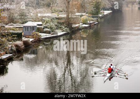 Ruderfahrer rudern auf dem Fluss Avon, während er nach einem leichten Schneefall im Winter durch Warwickshire fließt Stockfoto