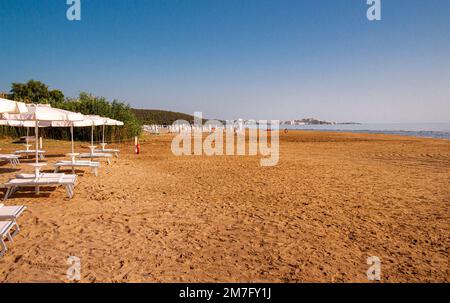 Spiaggia di Portonuovo Beach, ein Sandstrand mit Sonnenaufgang und im Hintergrund auf kalkhaltigen Felsen, die Altstadt von Vieste und der monolite Pizzomunno, Gargano Italien Stockfoto