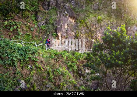 Frau mit einem großen Rucksack, die auf einem Wanderweg auf der Insel São Jorge auf den Azoren spaziert Stockfoto