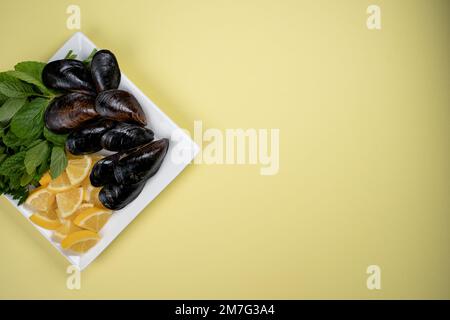 Die türkische Straße schmeckt gefüllte Muscheln mit Zitrone auf gelbem Hintergrund und Copy Space. Schwarze Schalentiere für Banner, Katalog oder Menü. Stockfoto