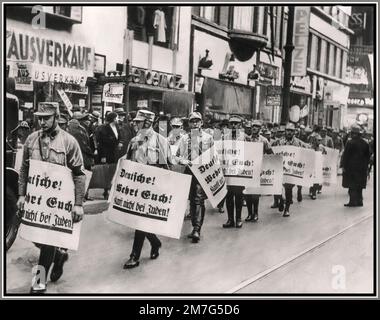 1930er Männer der Nazideutschland SA Sturmabteilung marschieren durch die Einkaufsstraßen Berlins und tragen Plakate gegen die jüdischen Ladenbesitzer Deutschlands. 1938 die Plakate tragen die Aufschrift "die Deutschen kämpfen zurück! Kaufen Sie nicht bei den Juden!" Die Verfolgung der Juden durch das Nazi-Regime erreichte ihren ersten Höhepunkt am 9. Und 10. November 1938 auf der sogenannten Kristallnacht. Stockfoto