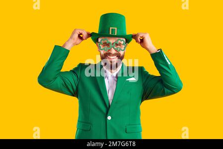 Lustiger Mann in grünem Anzug, Leprechaun-Hut und Kleebrille, der Spaß am St. Patrick's Day hat Stockfoto