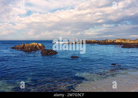 Meerblick auf die Monterey Bay mit wolkigem Himmel und felsiger Küste Stockfoto