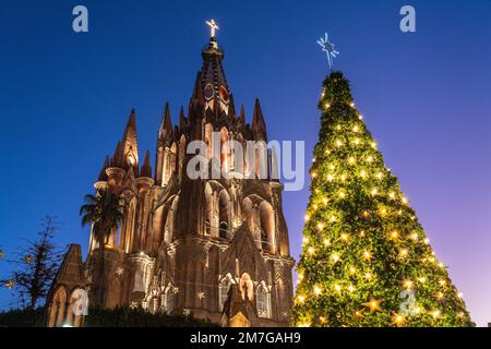 Der hell beleuchtete Weihnachtsbaum der Stadt neben der berühmten Kirche Parroquia de San Miguel Arcangel, die die Feiertage im zentralen historischen Viertel feiert, am 4. Januar 2023 in San Miguel de Allende, GTO, Mexiko. Stockfoto