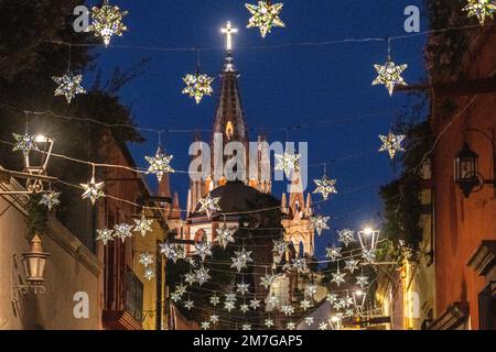 Farbenfrohe Sterndekorationen in Zinn umrahmen die berühmte Kirche Parroquia de San Miguel Arcangel, die das neue Jahr feiert, in der Aldama Street im zentralen historischen Viertel am 4. Januar 2023 in San Miguel de Allende, GTO, Mexiko. Stockfoto