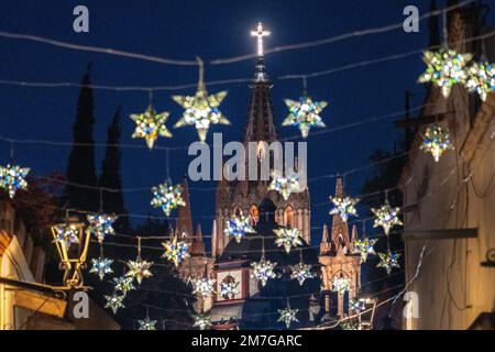 Farbenfrohe Sterndekorationen in Zinn umrahmen die berühmte Kirche Parroquia de San Miguel Arcangel, die das neue Jahr feiert, in der Aldama Street im zentralen historischen Viertel am 4. Januar 2023 in San Miguel de Allende, GTO, Mexiko. Stockfoto