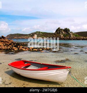 Ruhige Szene von Hangman Island von einem Sandstrand mit einem gefesselten Boot auf Bryher. In der Ferne ist Cromwells Castle auf Tresco, Scillies 28 Meile Stockfoto