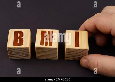 Geschäftskonzept. Auf einer schwarzen Oberfläche stellt ein Mann Würfel mit der Inschrift - BMI Stockfoto