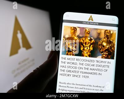 Person mit Smartphone und Website der Academy of Motion Picture Arts and Sciences (AMPAS) auf dem Bildschirm. Konzentrieren Sie sich auf die Mitte des Telefondisplays. Stockfoto