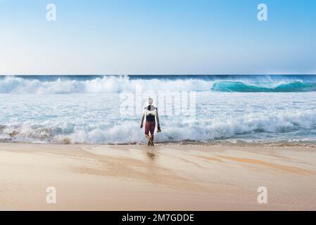 Ein Surffotograf, der in Banzai Pipeline, Oahu, Hawaii ins Meer kommt, Stockfoto